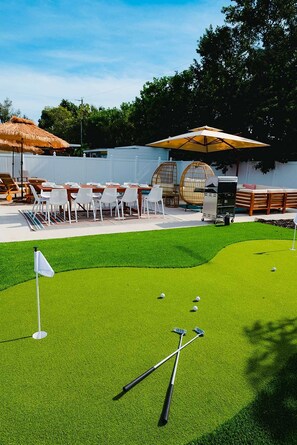 A backyard with a putting green, a dining area with chairs and tables, and a barbecue grill. - Sleeps 10 Outdoor Oasis Heated Pool Grill (Bradenton)