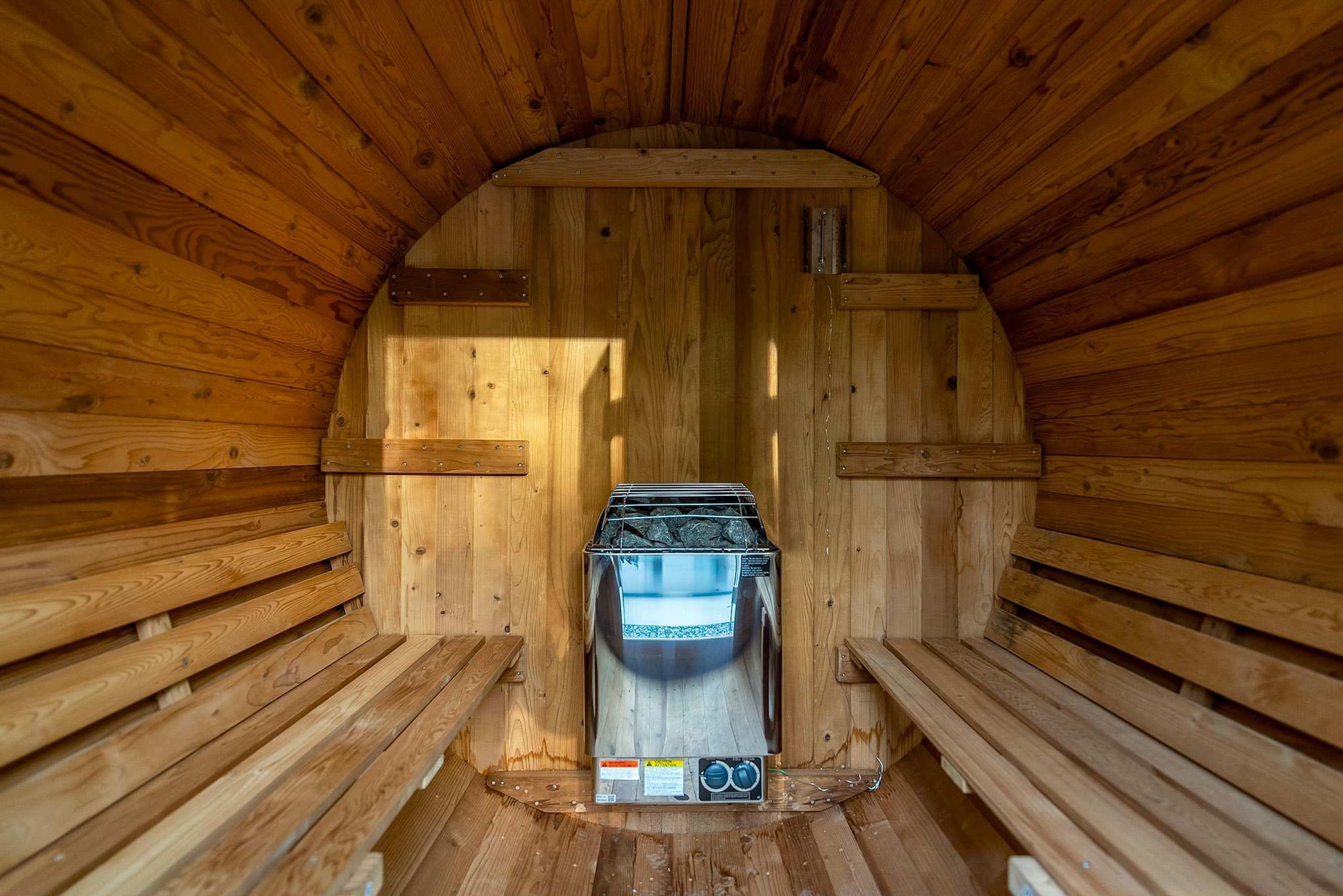 A sauna with a wooden interior, a bench, and a control panel.