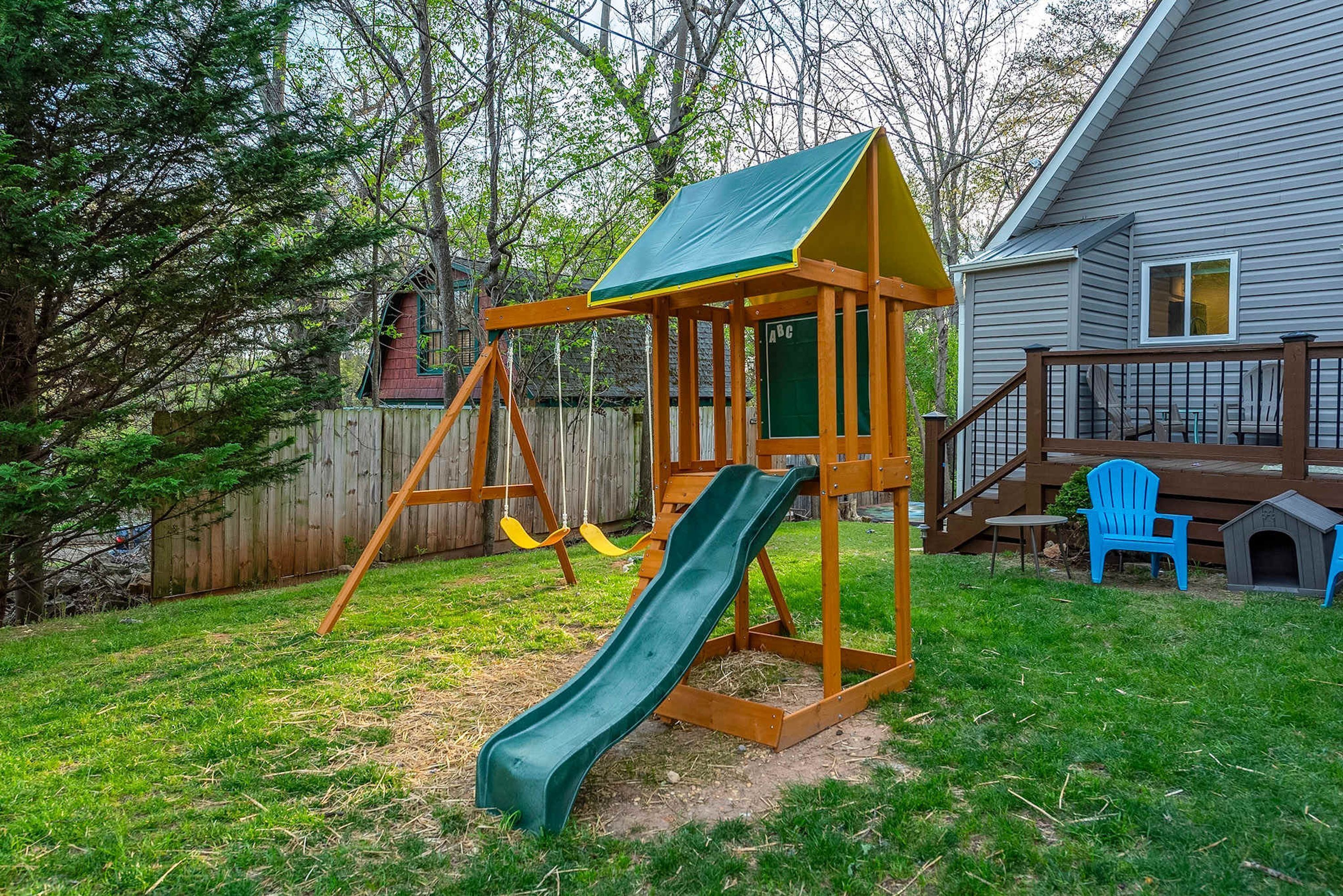 A wooden swing set with a slide in a backyard.