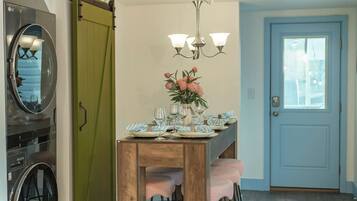 A dining area with a wooden table set for four, a chandelier, and a sliding door with a green panel.