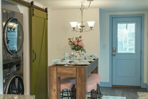 A dining area with a wooden table set for four, a chandelier, and a sliding door with a green panel. - New Stargazing Dome Hot Tub Sauna Firepit (Asheville)