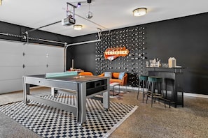 Quarto moderno com mesa de bilhar, espaço de bar e um letreiro de Tennessee na parede.