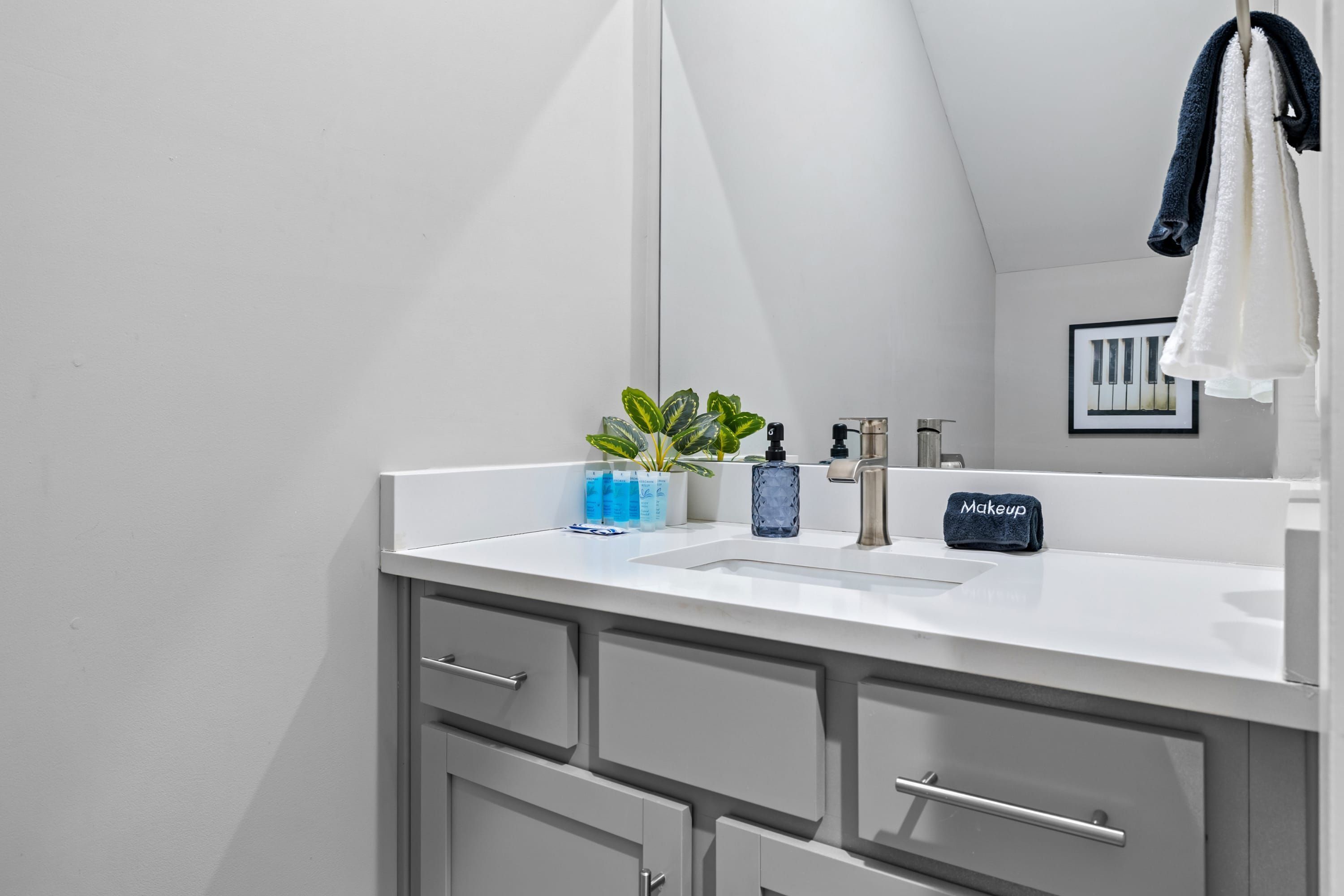 Une salle de bain moderne avec un meuble-lavabo blanc, un miroir et un porte-serviettes.
