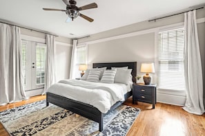 A bedroom with a bed, nightstands, a ceiling fan, and large windows with blinds. - Atlanta Beltline House City Center (Atlanta)