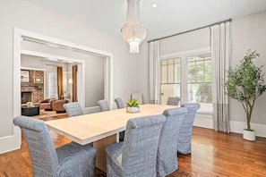 A dining room with a wooden table and patterned chairs, a chandelier, and a view of a living area with a fireplace. - Atlanta Beltline House City Center (Atlanta)