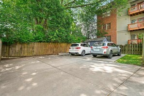 A residential driveway with two cars parked, a wooden fence, and a building with a balcony. - Atlanta Beltline House City Center (Atlanta)