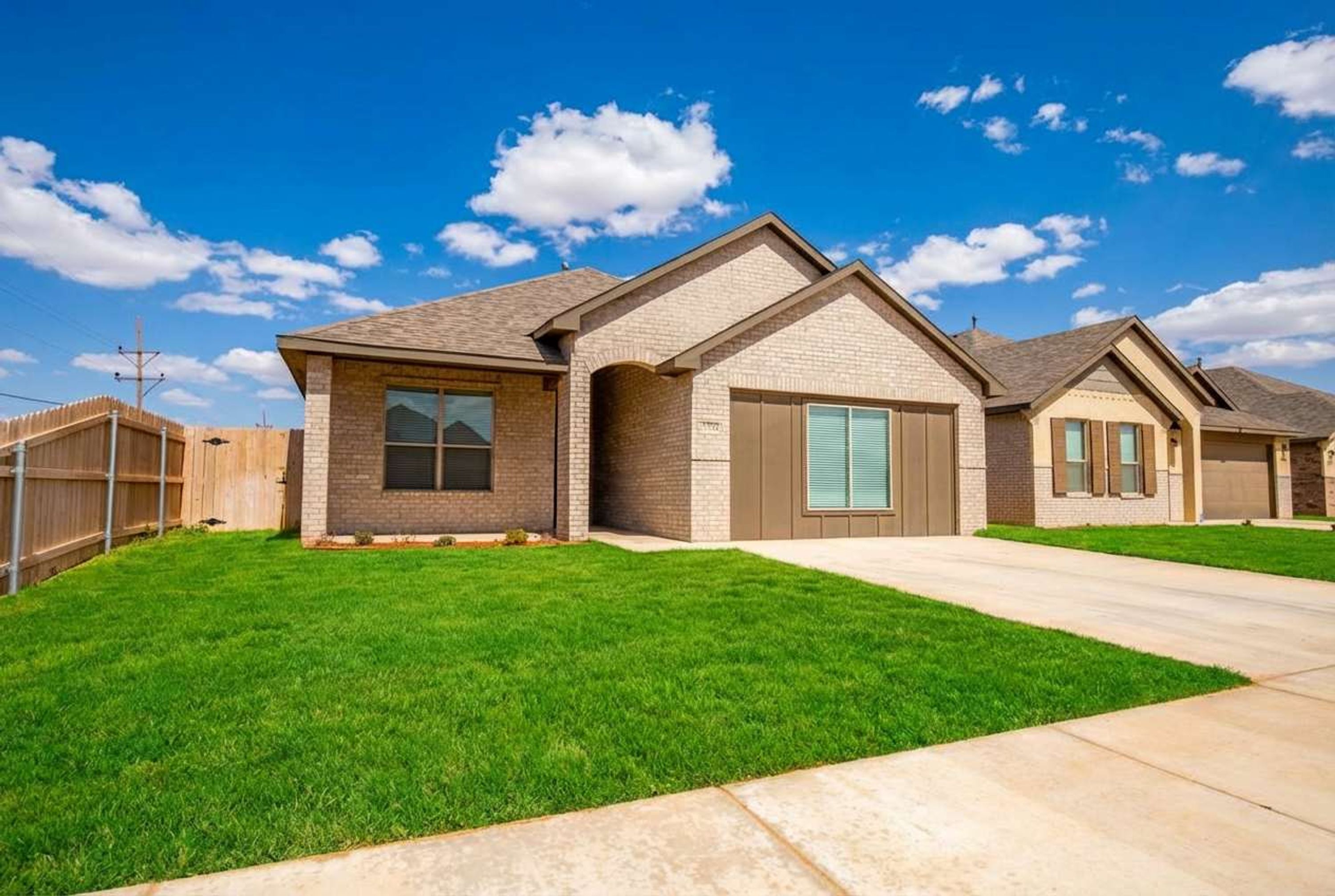 A residential neighborhood with single-family homes featuring brick exteriors, pitched roofs, and front yards with manicured lawns.