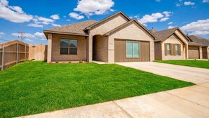 A residential neighborhood with single-family homes featuring brick exteriors, pitched roofs, and front yards with manicured lawns. - 10 Minutes to Stadium Spacious 3BR Gameroom (Lubbock)