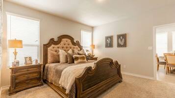 A bedroom with a large bed, two bedside tables, a dresser, and a chair.