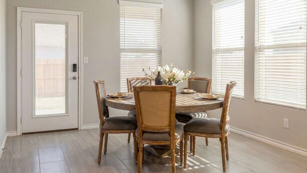 A dining area with a round table, six chairs, and a vase of flowers. - 10 Minutes to Stadium Spacious 3BR Gameroom (Lubbock)