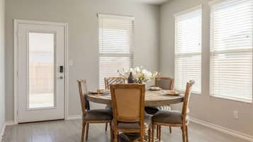 A dining area with a round table, six chairs, and a vase of flowers.