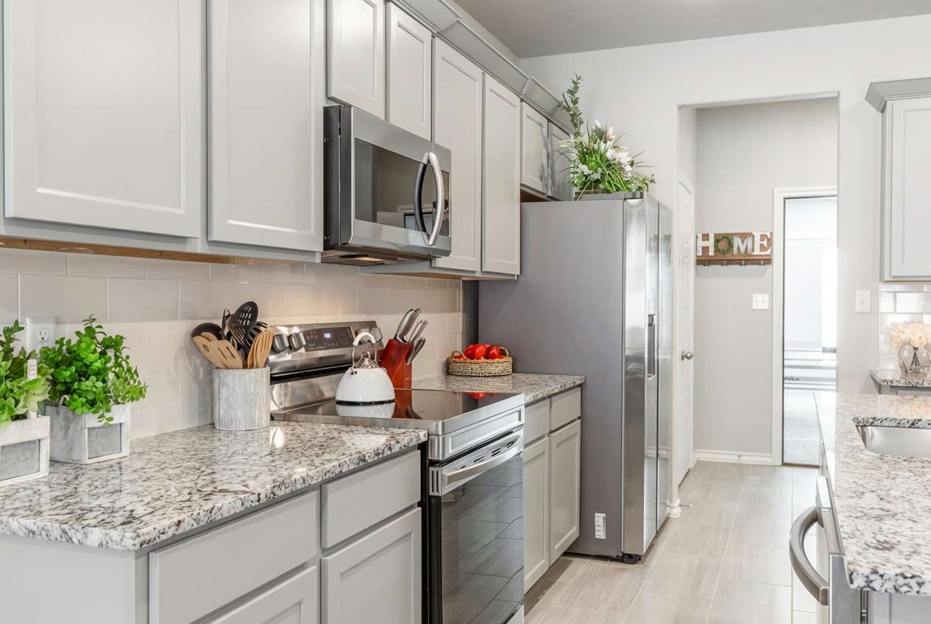A modern kitchen with stainless steel appliances, white cabinetry, and granite countertops.