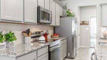 A modern kitchen with stainless steel appliances, white cabinetry, and granite countertops.