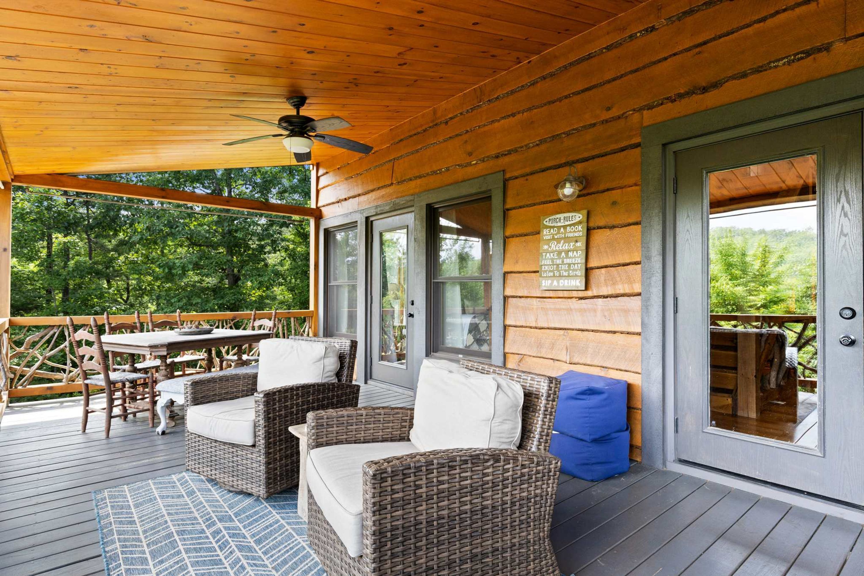A covered outdoor area with wicker furniture, a ceiling fan, and a sign with rules.