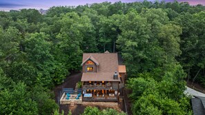 A two-story log cabin with a deck and outdoor seating area, surrounded by dense forest. - EZ Come EZ Geaux - Stunning Mtn Views - Hot Tub (Blue Ridge)