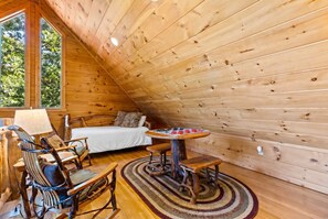 A cozy cabin interior with a bed, a dining table, and a chair.