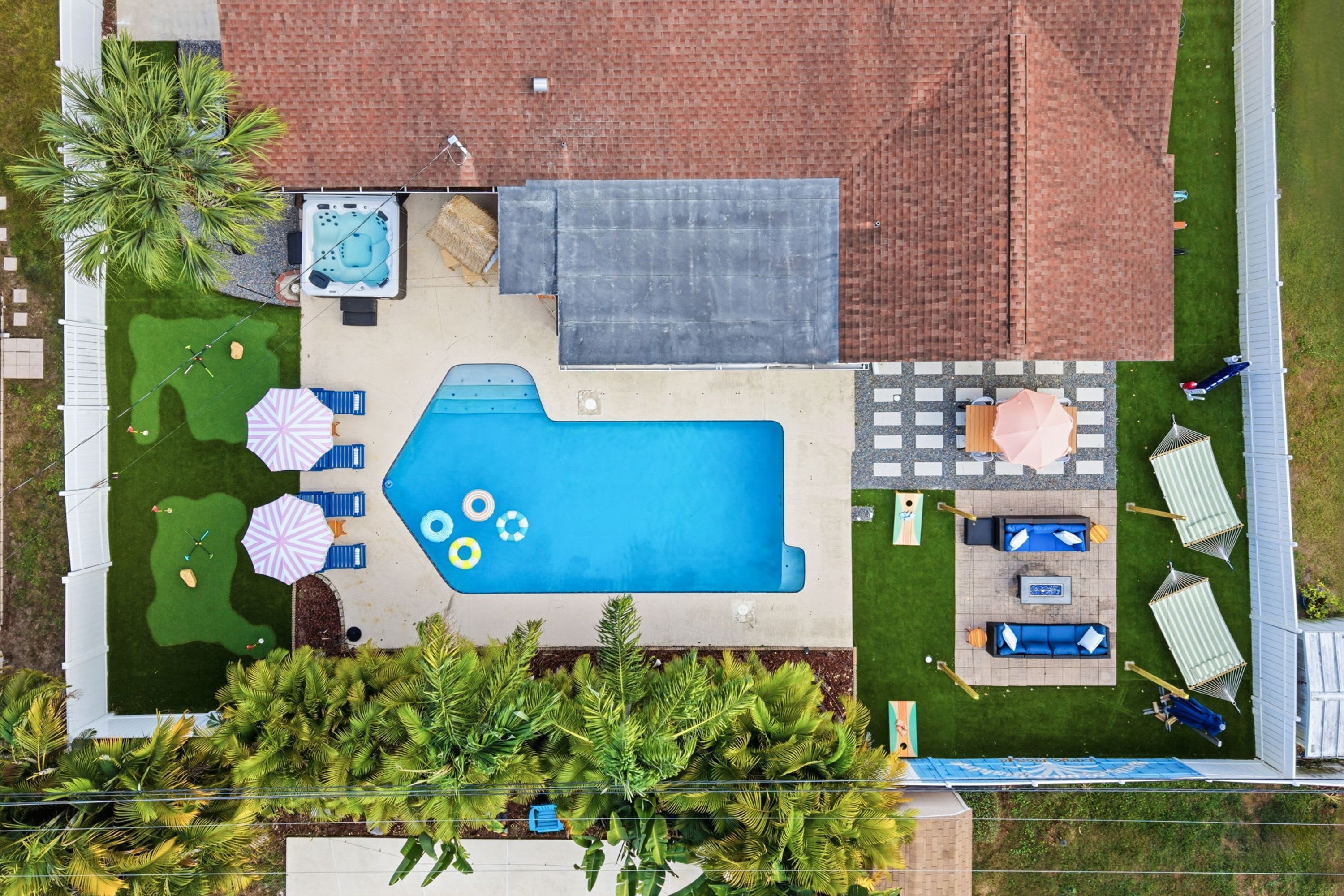 A rooftop swimming pool with a hot tub, lounge chairs, and umbrellas.