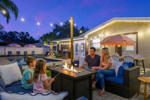A poolside area with a fire pit, outdoor seating, and string lights. - Tropical Tee - Putt Putt - Pool - Hot Tub - Bikes (Largo)