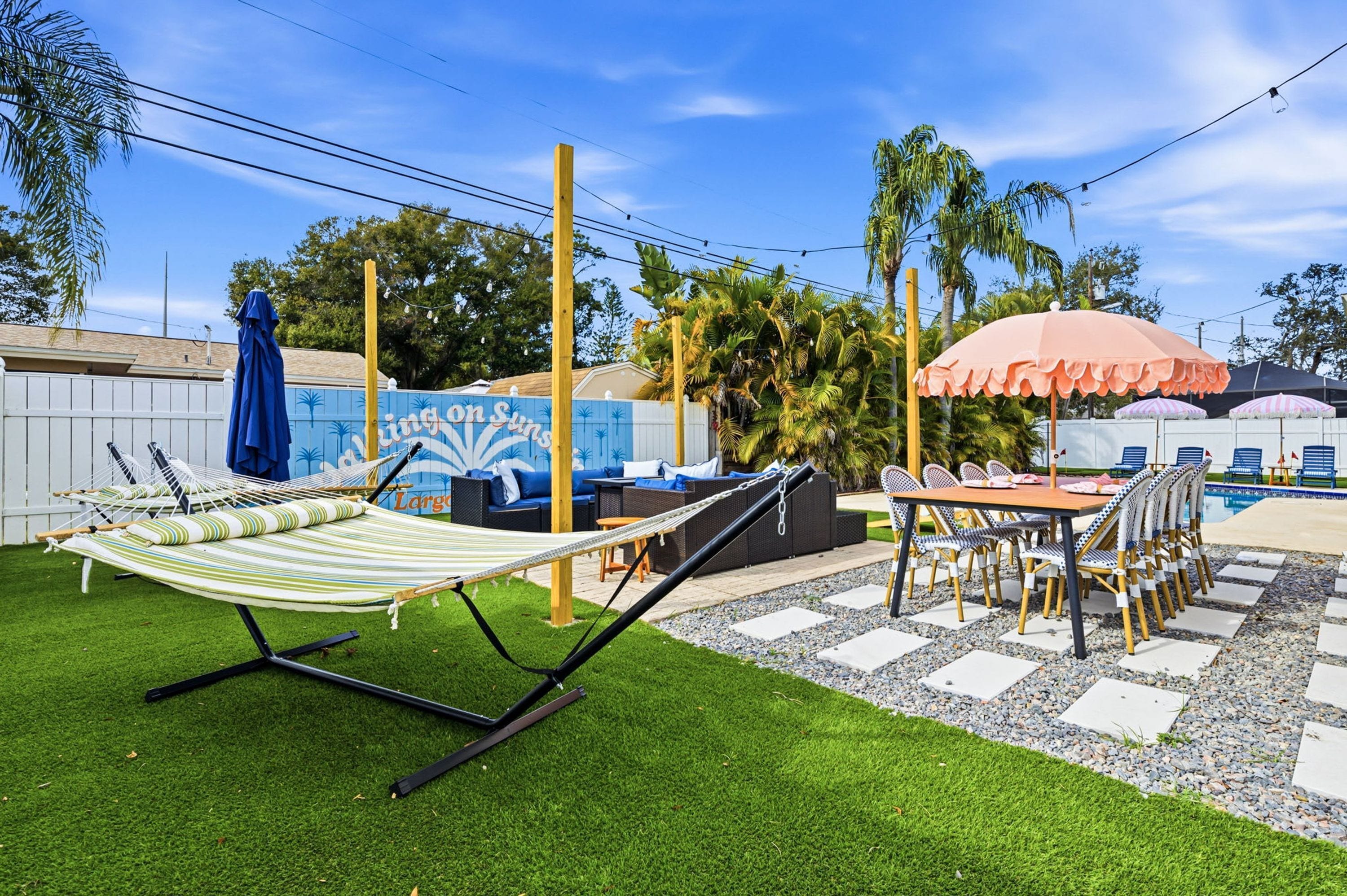 A backyard with a hammock, outdoor seating, and a pool area.