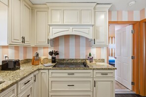 A kitchen with white cabinetry, a granite countertop, a toaster, and a stove. - Tropical Tee - Putt Putt - Pool - Hot Tub - Bikes (Largo)