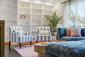 A living room with striped armchairs, a sofa, a coffee table, and a bookshelf. - Tropical Tee - Putt Putt - Pool - Hot Tub - Bikes (Largo)
