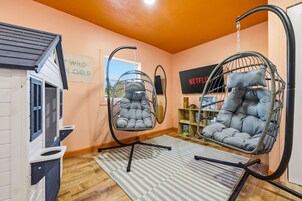 A room with two hanging chairs, a bookshelf, and a sign that reads 'WILD CHILD'.