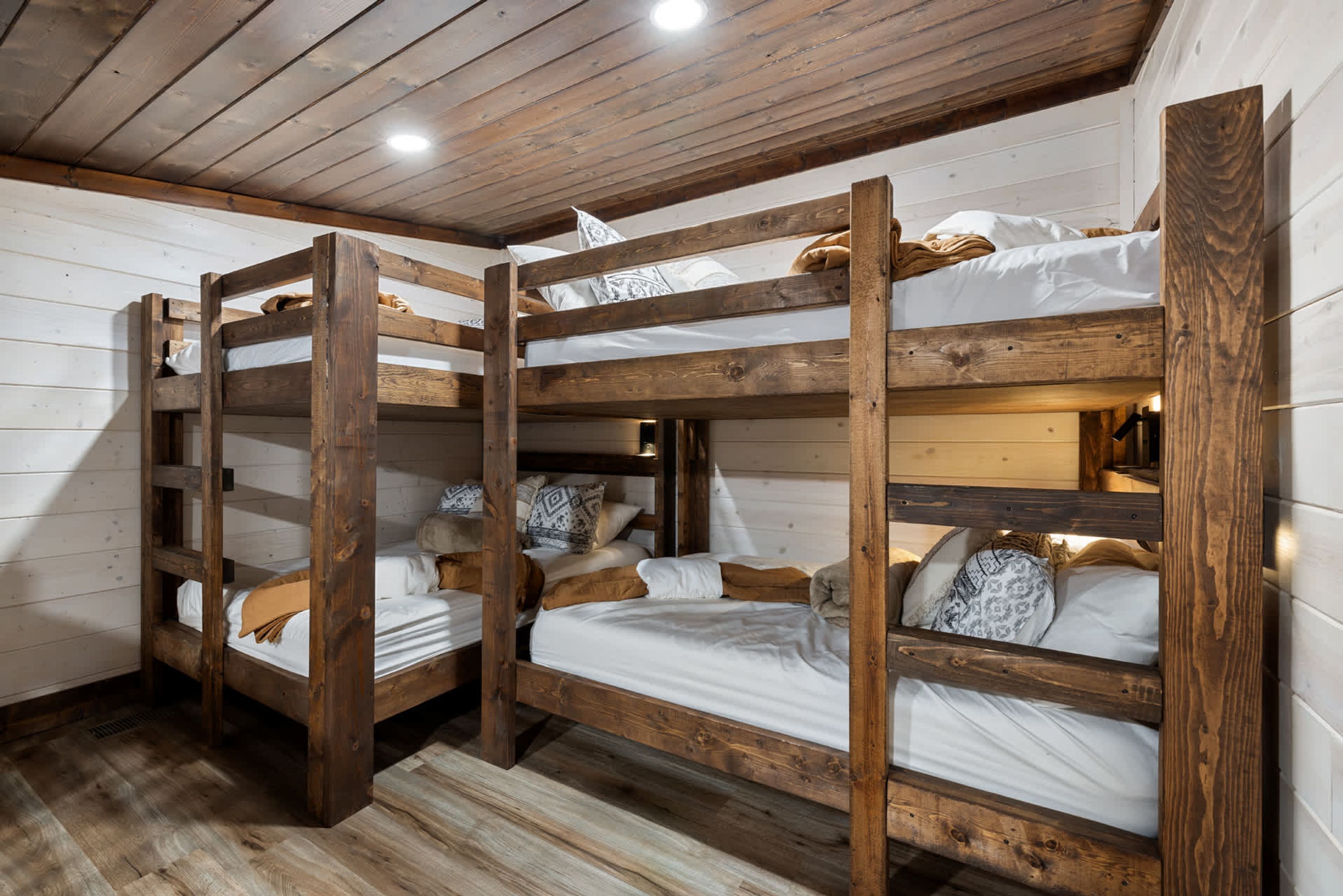 A bunk bed room with wooden frames and white bedding.