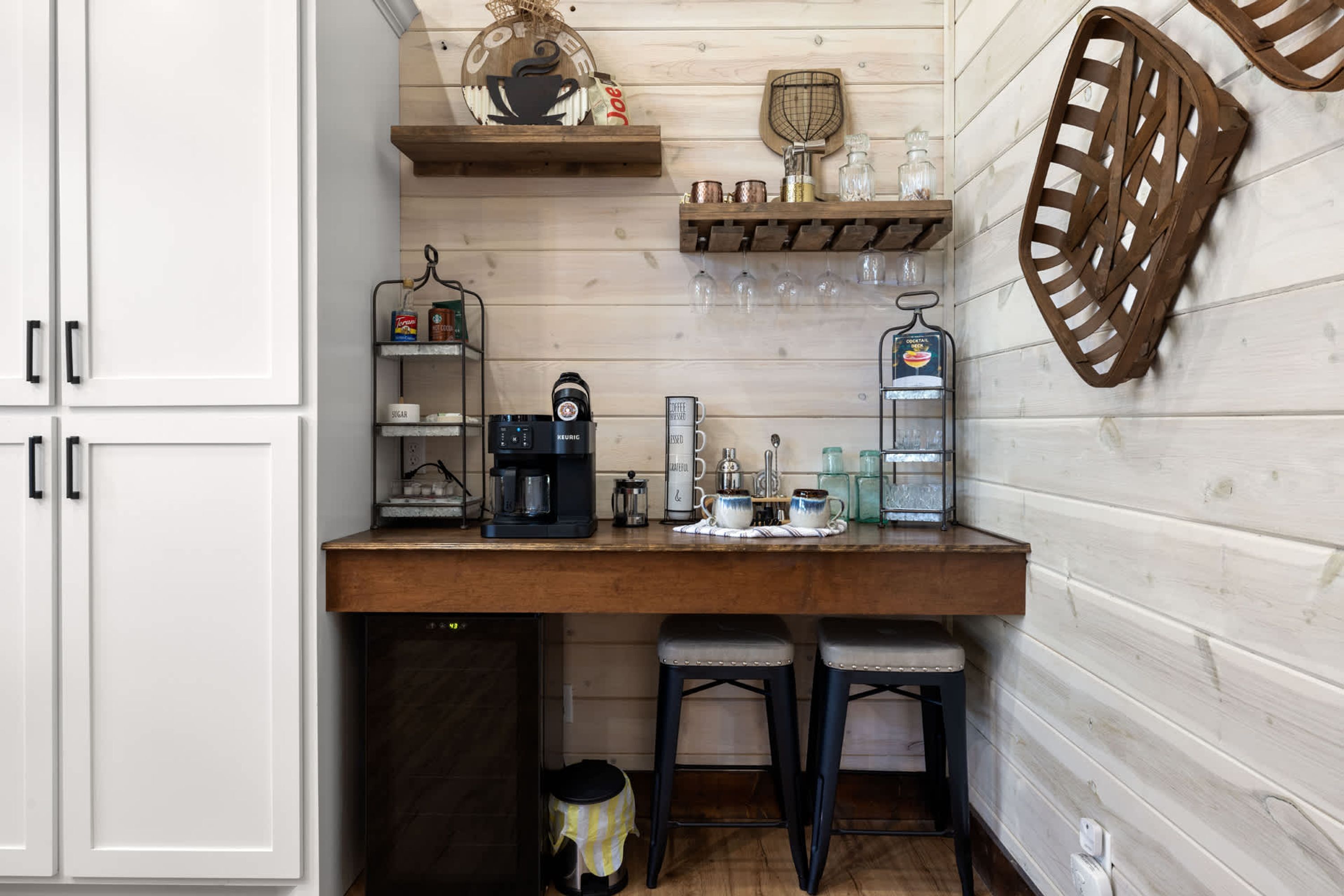 A kitchen with a wooden countertop, a coffee maker, and bar stools.