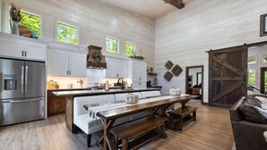 A spacious kitchen with a central island, wooden flooring, and a large dining area with a bench. - Broken Bow Luxury Cabin Hot Tub Playset Games (Broken Bow)