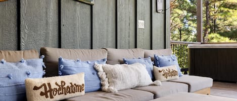 Une terrasse en bois dotée d’un espace salon confortable agrémenté de coussins décoratifs.