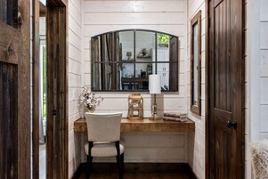 Una habitación pequeña con un escritorio de madera, una silla, un espejo y una ventana.