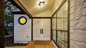 A covered entrance with a tiled floor, a circular window, and a door with a patterned design. - Riverwalk Villa Game Room Grill Heated Pool (San Antonio)