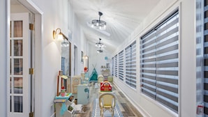 A hallway with a wooden floor, a toy play area, and a large window with blinds. - Riverwalk Villa Game Room Grill Heated Pool (San Antonio)