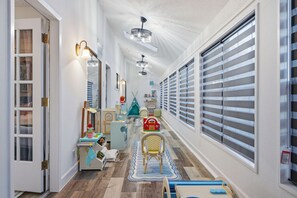 Ein Flur mit Holzboden, einer Spielecke für Kinder und einem großen Fenster mit Jalousien.