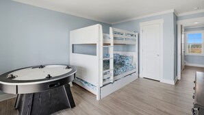 Ein Zimmer mit Stockbetten, einem runden Tisch und einer Tür zu einem anderen Raum.
