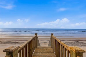 Una pasarela de madera que conduce a una playa con cielo despejado.