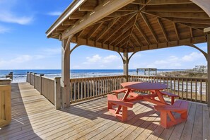 A wooden deck with a picnic table and benches overlooking a beach. - Steps to the Sand Sleeps 12 Hot Tub Grill (Sneads Ferry)