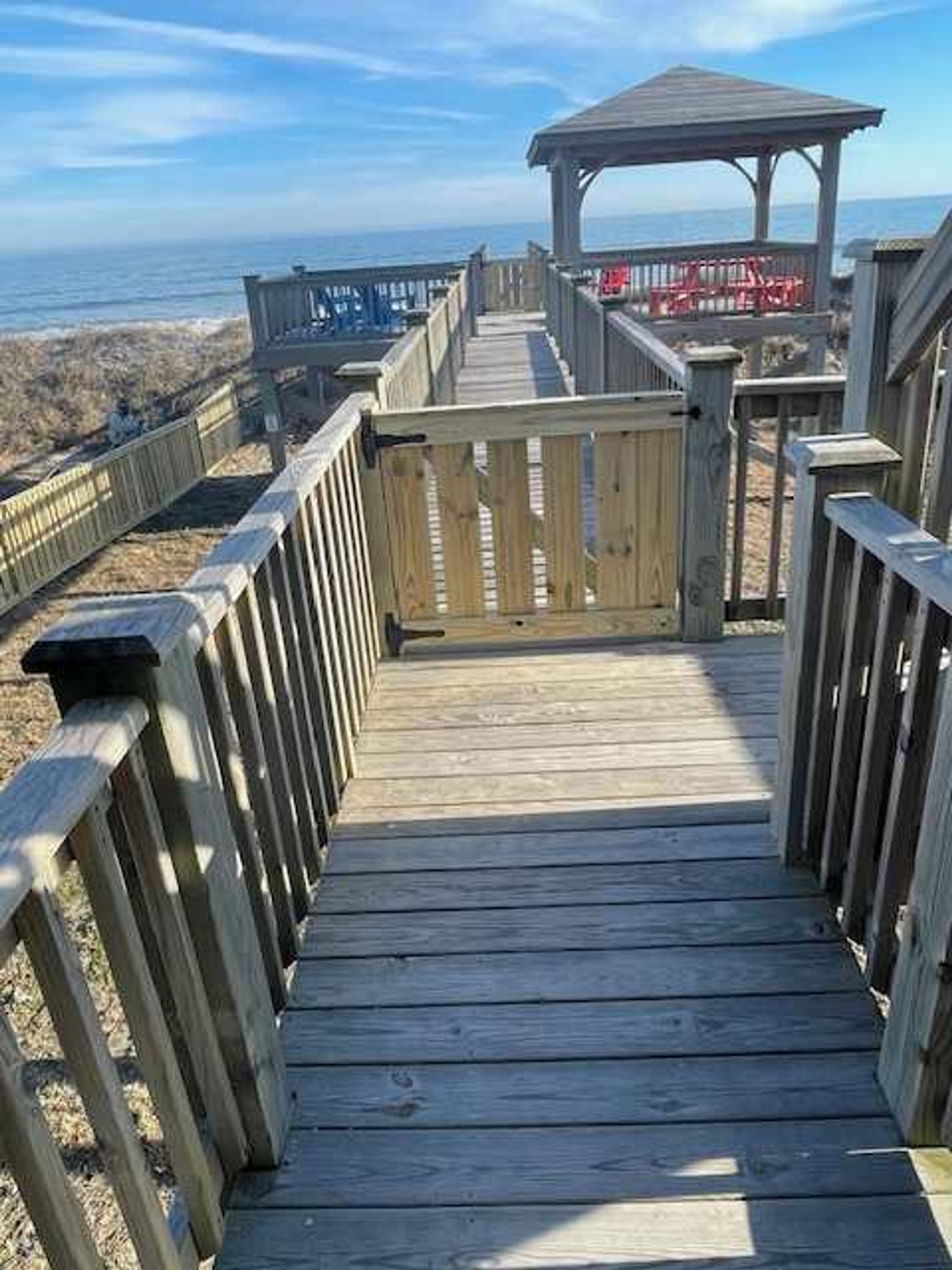 A wooden boardwalk leading to a gazebo with a view of the ocean.