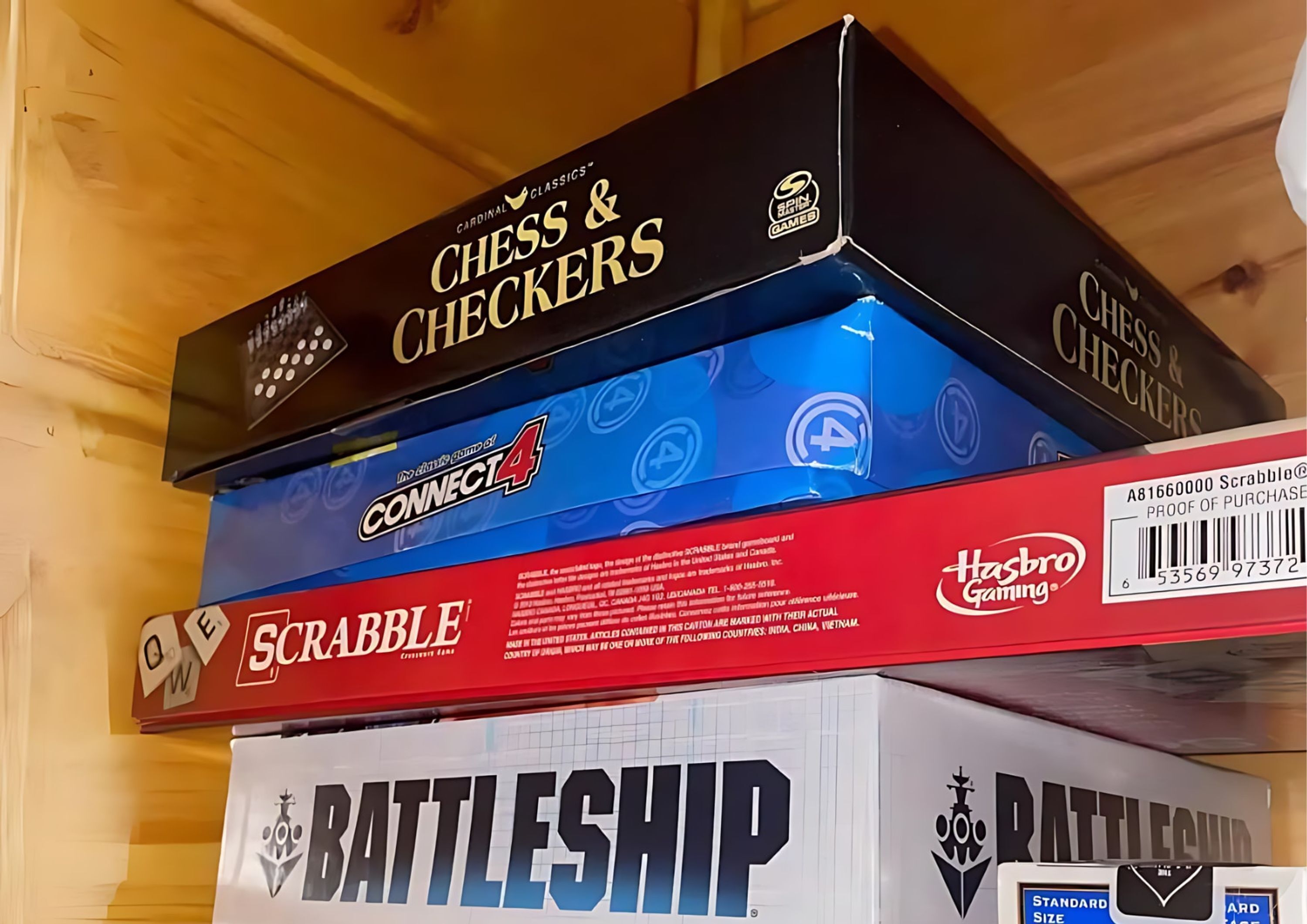 A stack of board games including Chess & Checkers, Connect4, Scrabble, and Battleship.