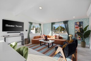 Ein modernes Wohnzimmer mit einer Couch, einem Couchtisch und einem an der Wand montierten Flachbildfernseher.