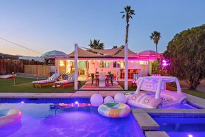 Ein Garten mit Pool, Schwimmnudel und einem Haus mit Außenbereich zum Sitzen.