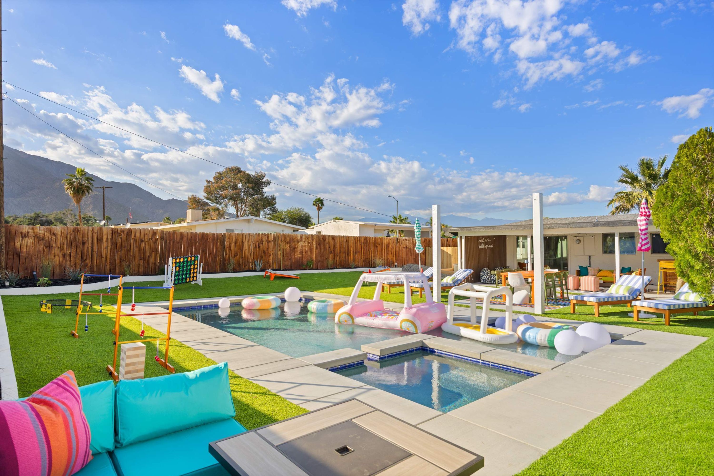 A backyard with a swimming pool, inflatable pool toys, and a wooden fence.