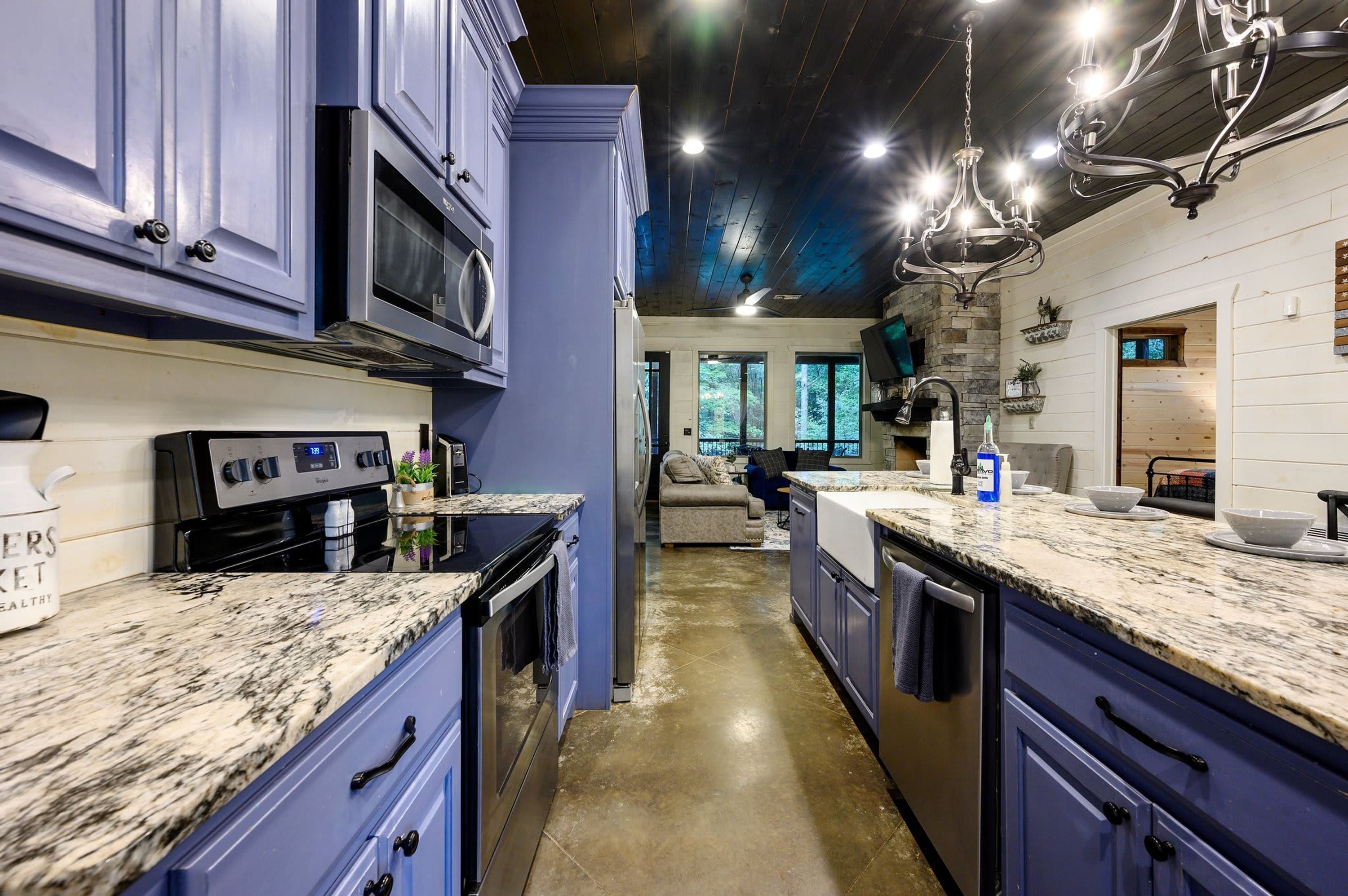 A modern kitchen with granite countertops, stainless steel appliances, and a view into the living area.