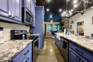 Una cocina moderna con encimeras de granito, electrodomésticos de acero inoxidable y vista al área social.