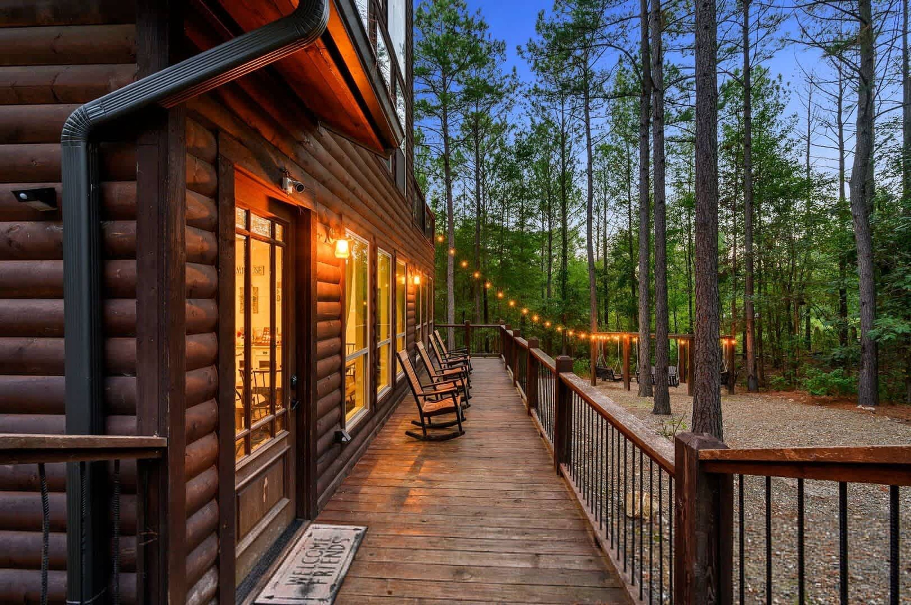 Une cabane en bois dotée d’une terrasse, entourée d’arbres.