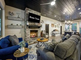 Una sala moderna con chimenea de piedra, un televisor y un rincón de estar acogedor.