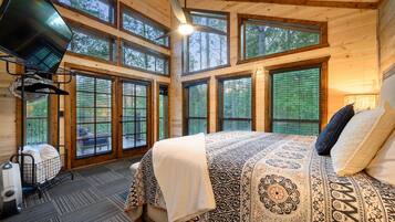 A bedroom with a large bed, multiple windows, and a ceiling fan.