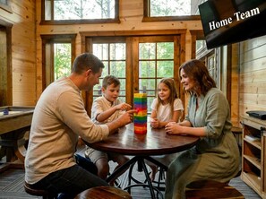 A family playing with a colorful block tower in a wooden room with large windows. - Aspen Creek Lodge Spacious Luxury Cabin Retreat (Broken Bow)