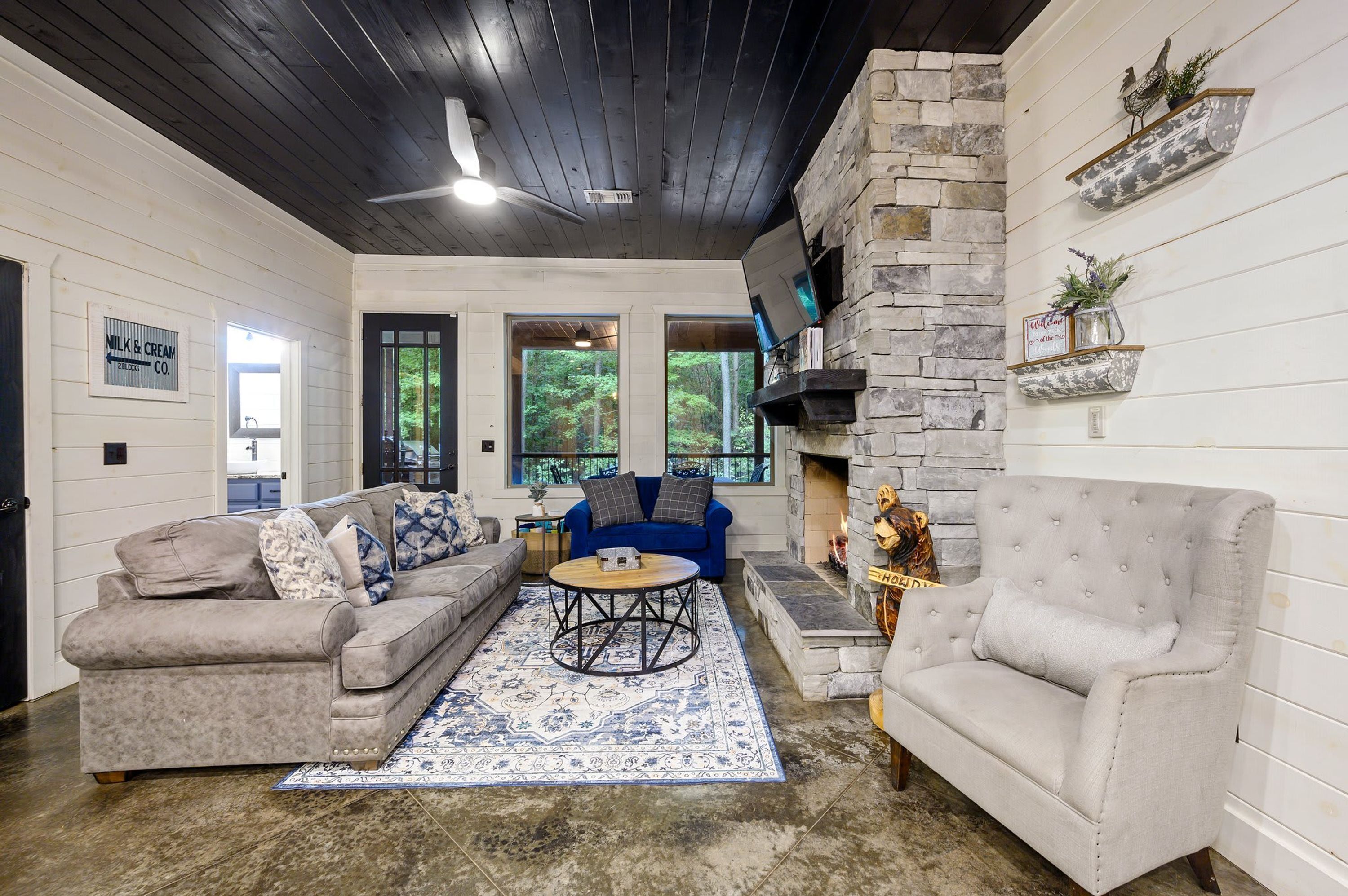 A cozy living room with a stone fireplace, a blue sofa, and a grey armchair.