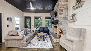 A cozy living room with a stone fireplace, a blue sofa, and a grey armchair.